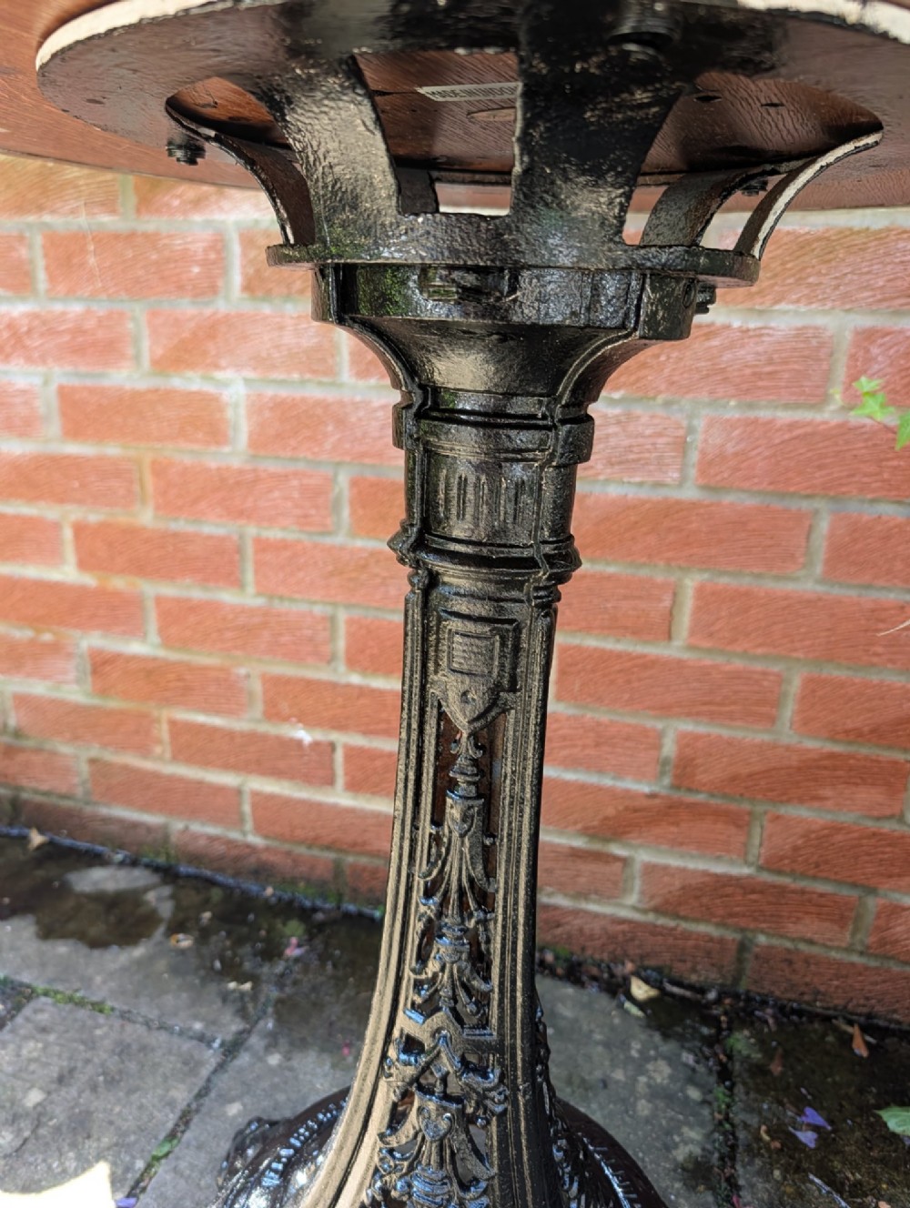 A Victorian cast iron garden set featuring a circular table with a copper top alongside four black ornate openwork chairs. View IV