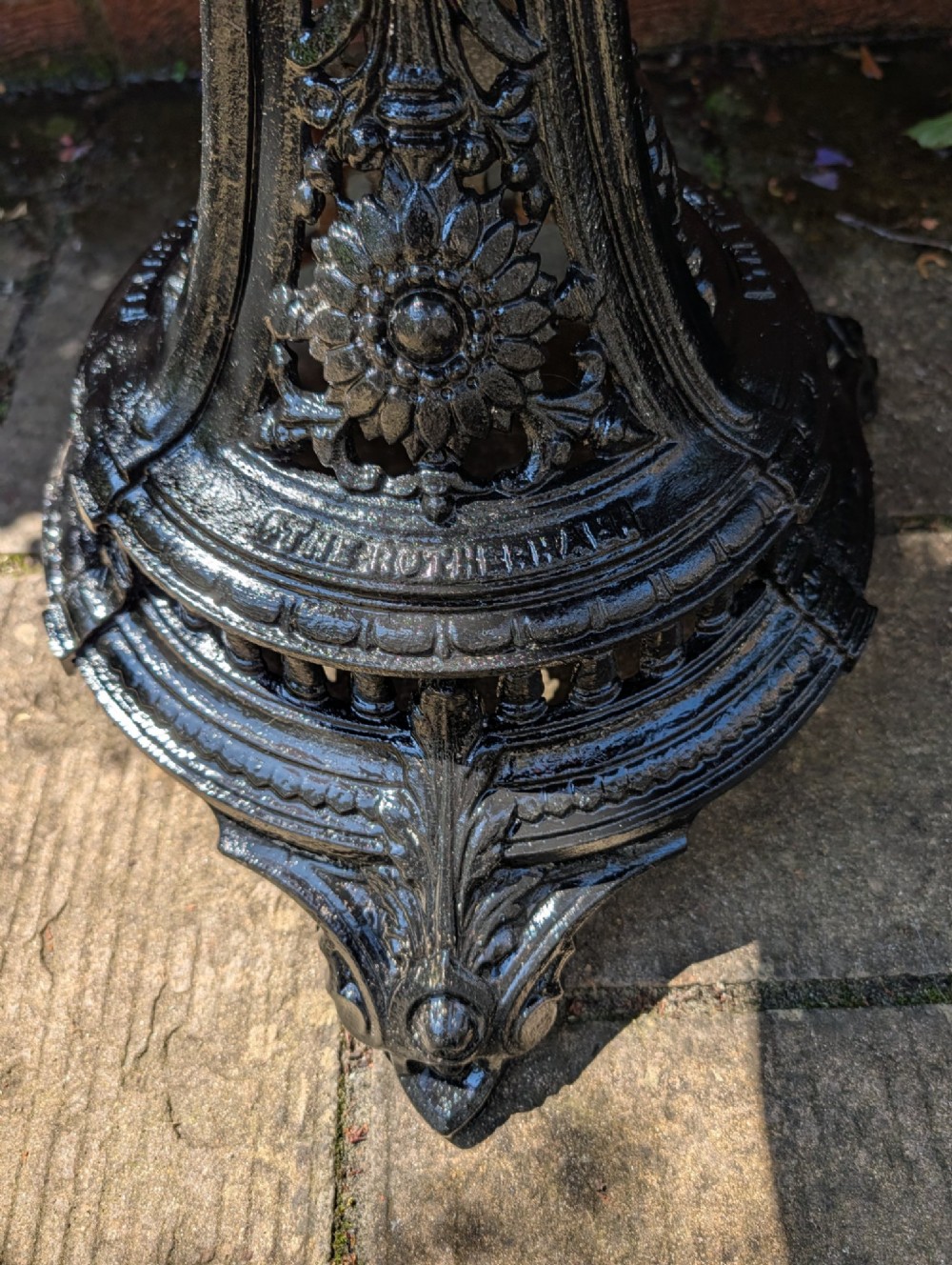 A Victorian cast iron garden set featuring a circular table with a copper top alongside four black ornate openwork chairs. View V