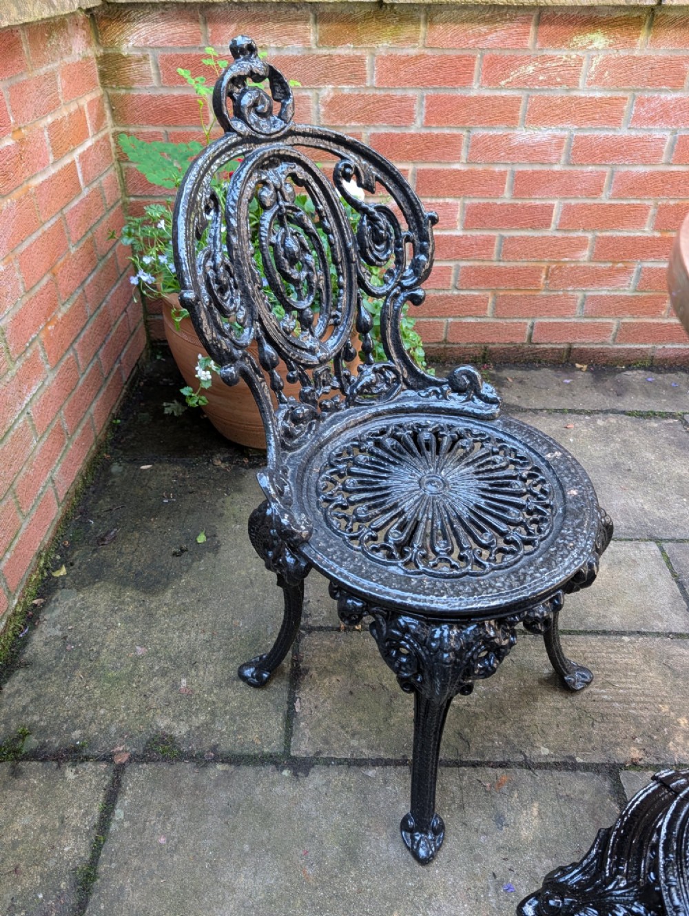 A Victorian cast iron garden set featuring a circular table with a copper top alongside four black ornate openwork chairs. View VII