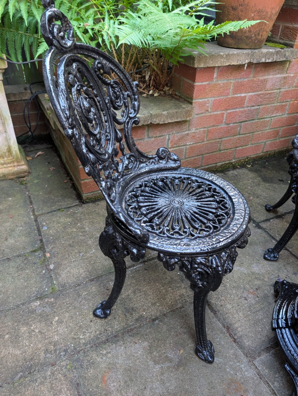 A Victorian cast iron garden set featuring a circular table with a copper top alongside four black ornate openwork chairs. View VIII