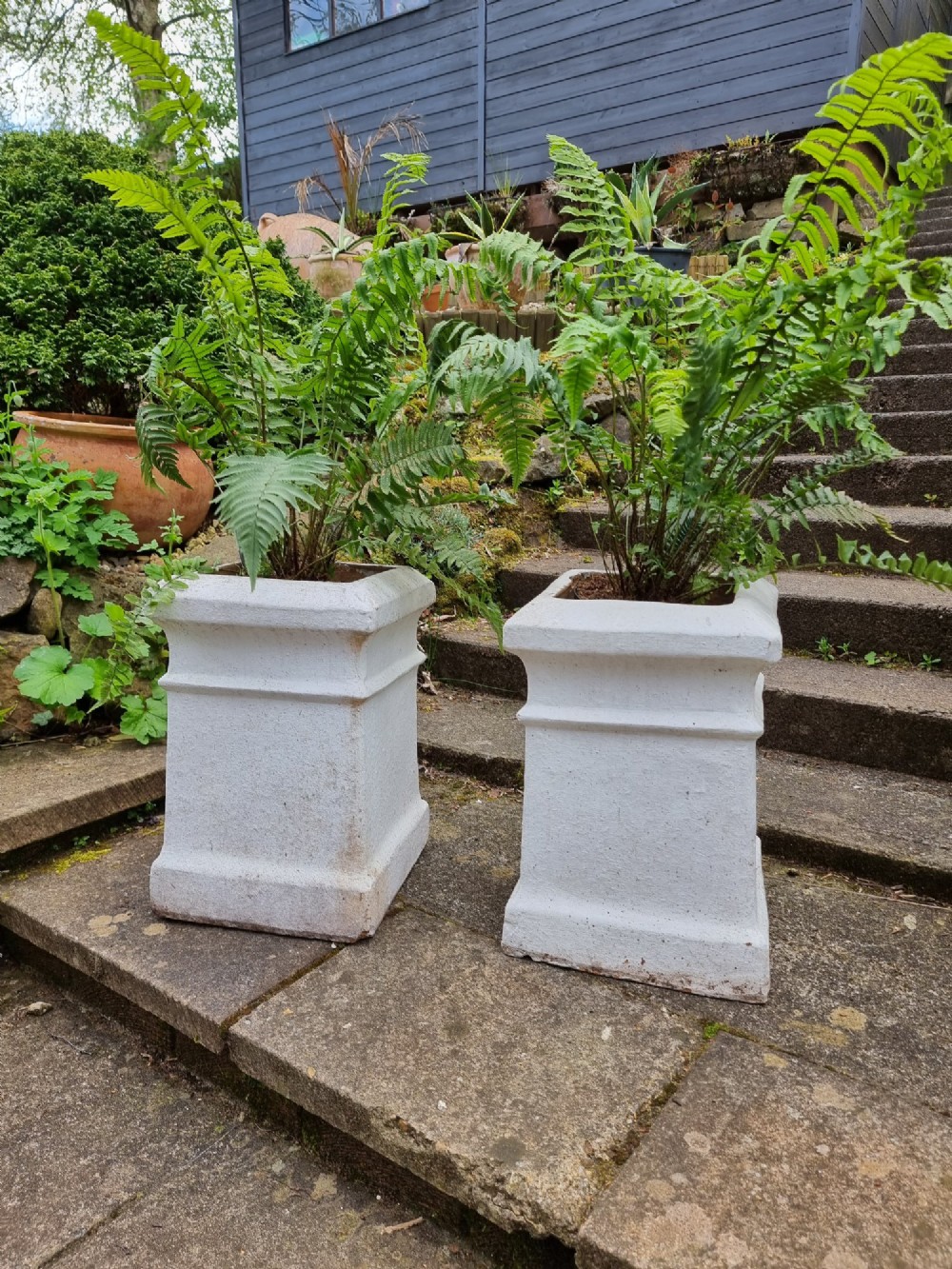 A pair of 19th-century square white-painted terracotta chimney pot pedestals with moulded rims resting on stone steps. View II