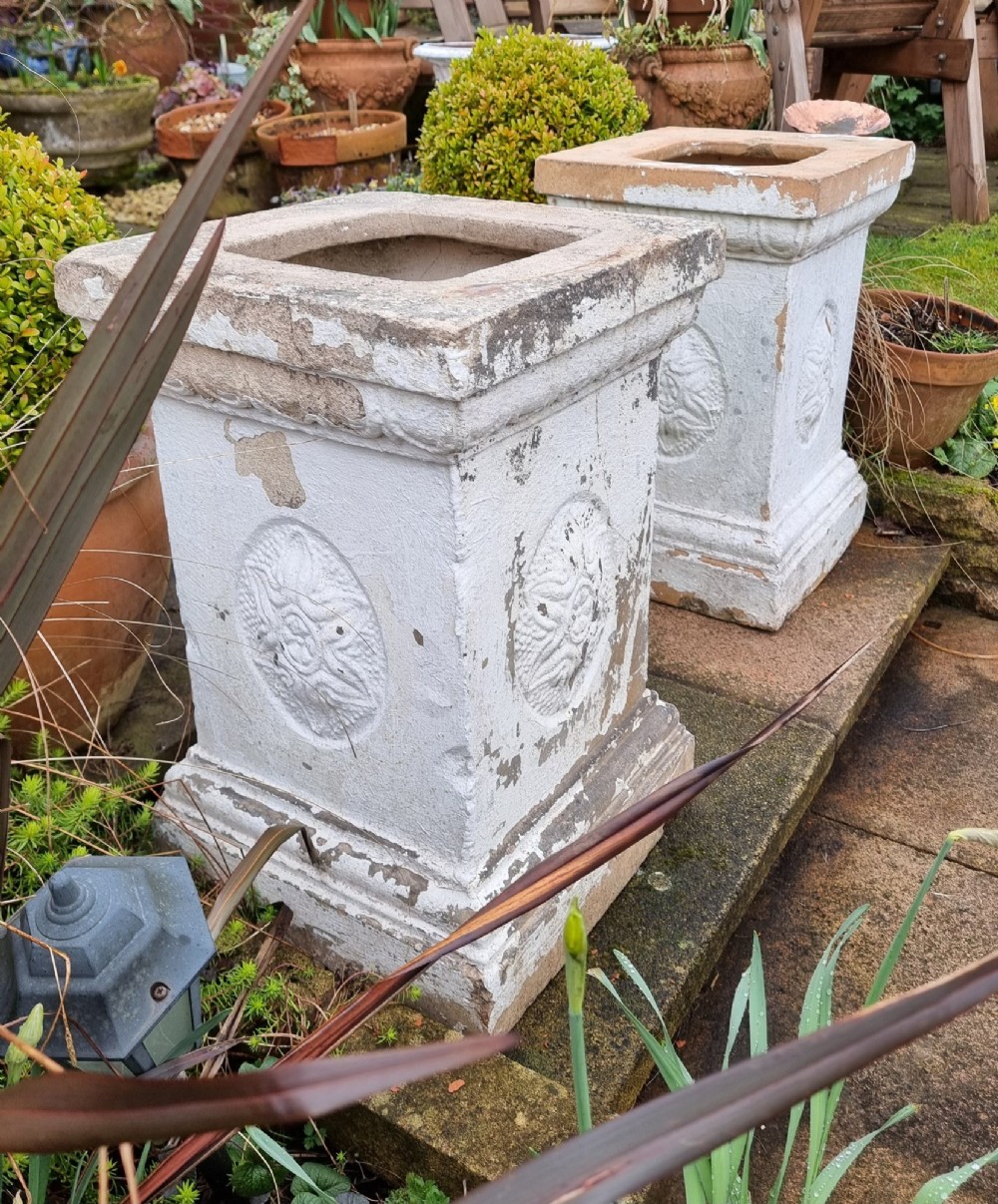 A pair of square weathered terracotta garden pedestals featuring moulded top rims and central circular floral medallion motifs. View IV