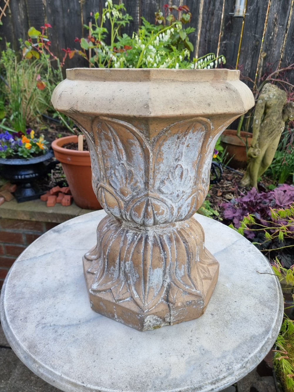 A 19th-century terracotta garden urn featuring carved leaf moulding, an octagonal top rim, and a flared pedestal base with weathered patina. View VII