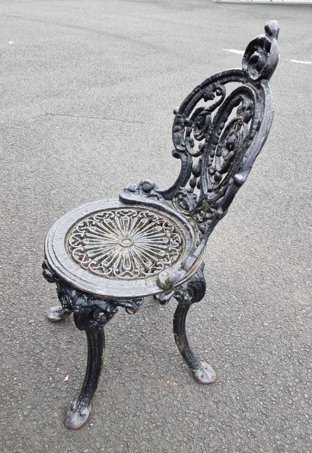 A black ornate cast-iron garden set featuring a circular stone-topped pedestal table and four matching pierced-back chairs. View VI
