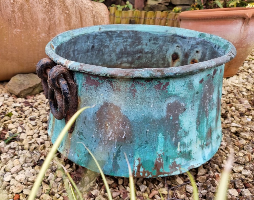 A large circular 19th-century copper vessel with a heavy verdigris green patina and dual wrought-iron drop handles. View V