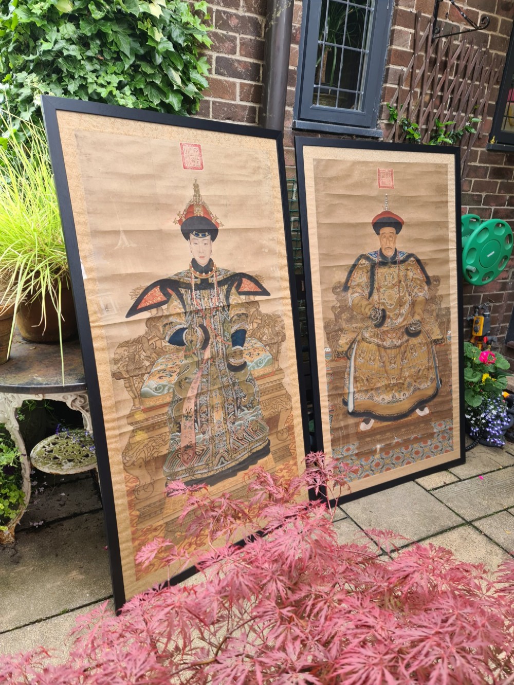 A large pair of framed Chinese ancestral portraits depicting a male and female figure in traditional formal court robes seated on ornate thrones.