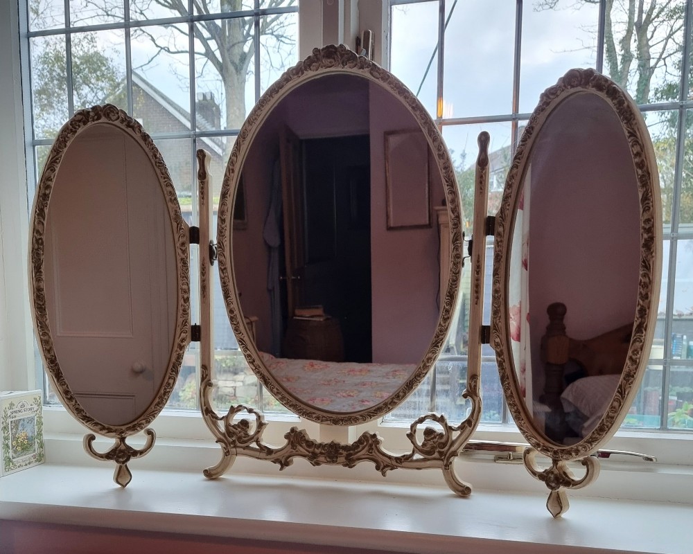 A 1930s cream-painted triple vanity mirror featuring three oval glass panels set in ornate scrollwork frames. View II