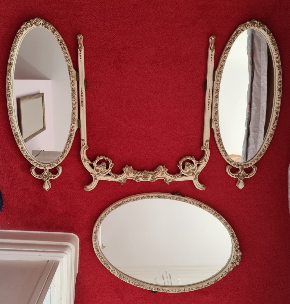 A 1930s cream-painted triple vanity mirror featuring three oval glass panels set in ornate scrollwork frames. View XI