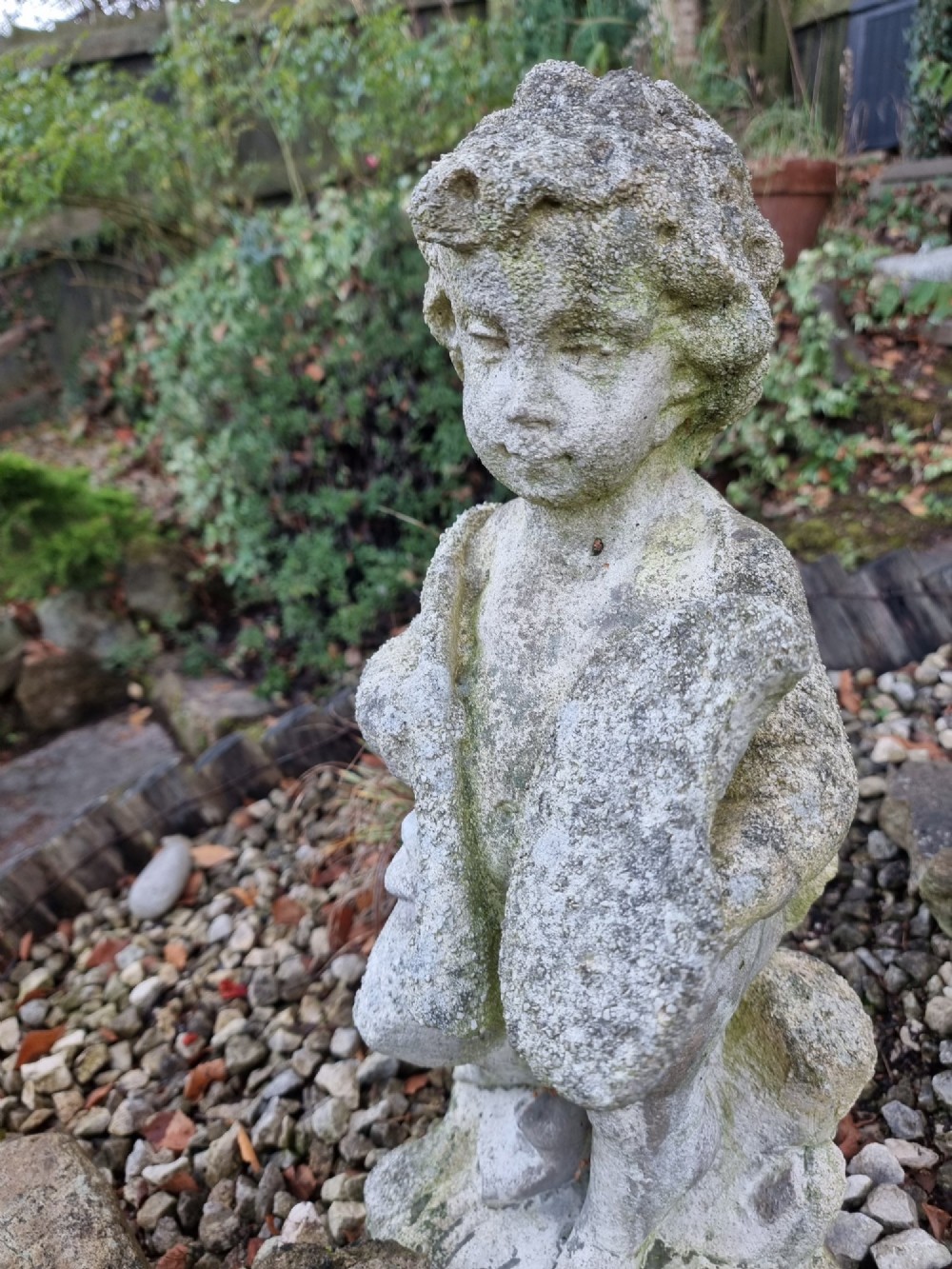 A pair of weathered grey reconstituted stone garden statues depicting classical musical cherubs holding instruments. View VII