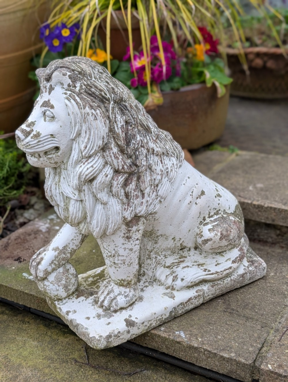 A pair of 19th-century French weathered off-white cast stone Medici lion statues seated on rectangular plinths, each resting a paw on a sphere. View III