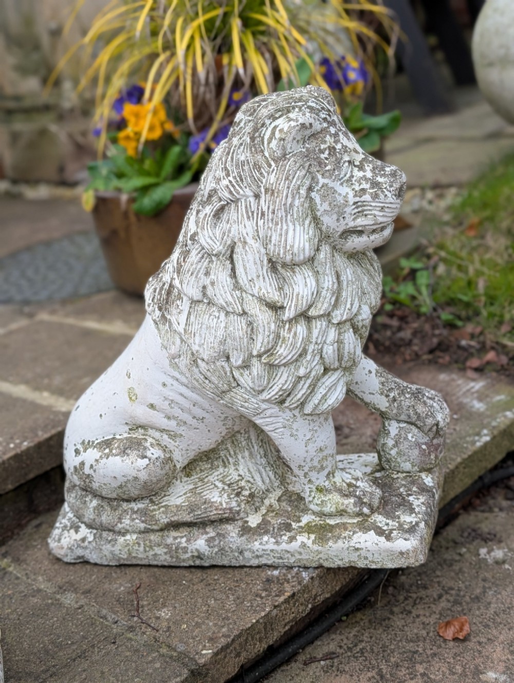 A pair of 19th-century French weathered off-white cast stone Medici lion statues seated on rectangular plinths, each resting a paw on a sphere. View IV