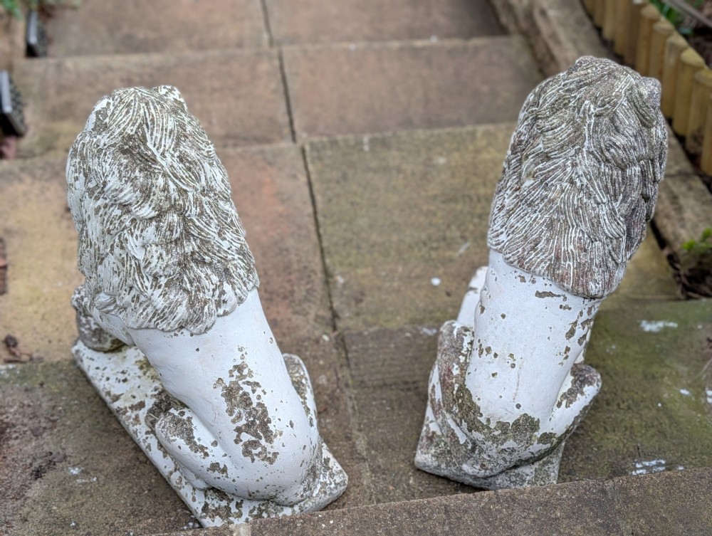 A pair of 19th-century French weathered off-white cast stone Medici lion statues seated on rectangular plinths, each resting a paw on a sphere. View V