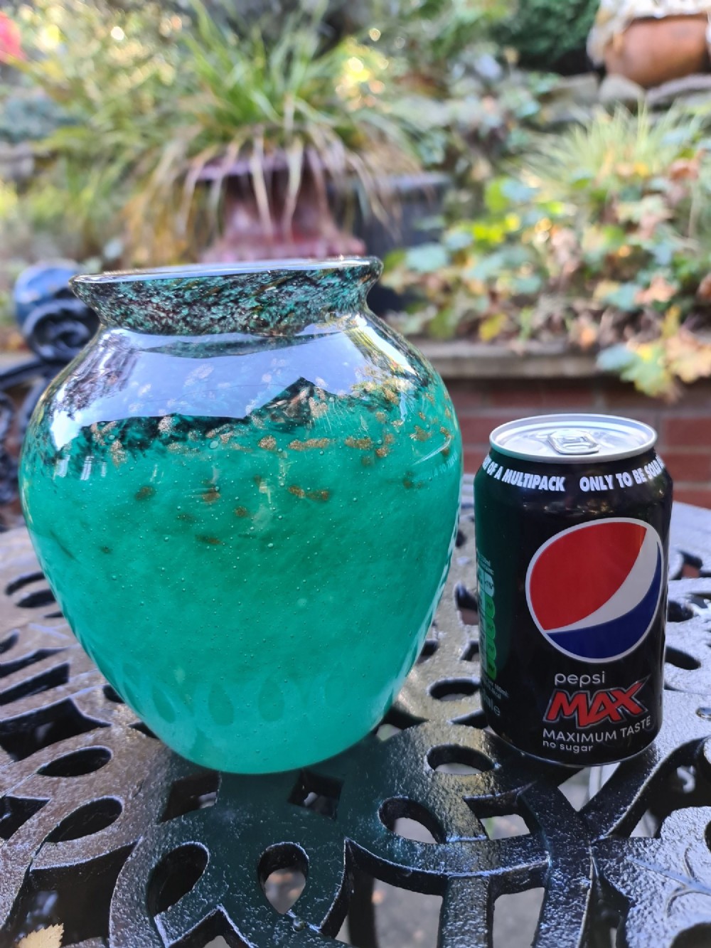 A rounded emerald green blown glass vase featuring a dark mottled rim, flared lip, and suspended gold aventurine flecks. View II