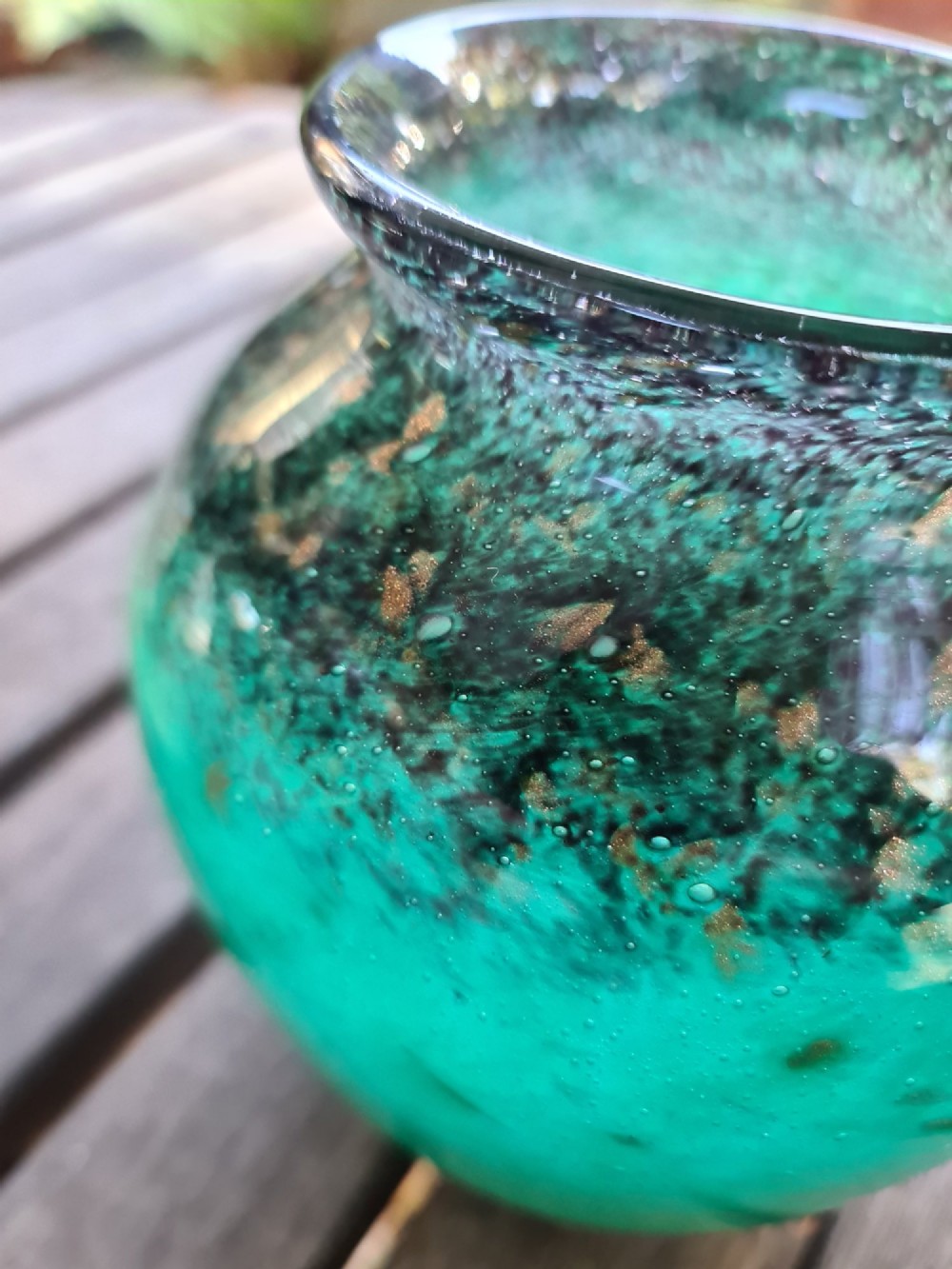 A rounded emerald green blown glass vase featuring a dark mottled rim, flared lip, and suspended gold aventurine flecks. View IV