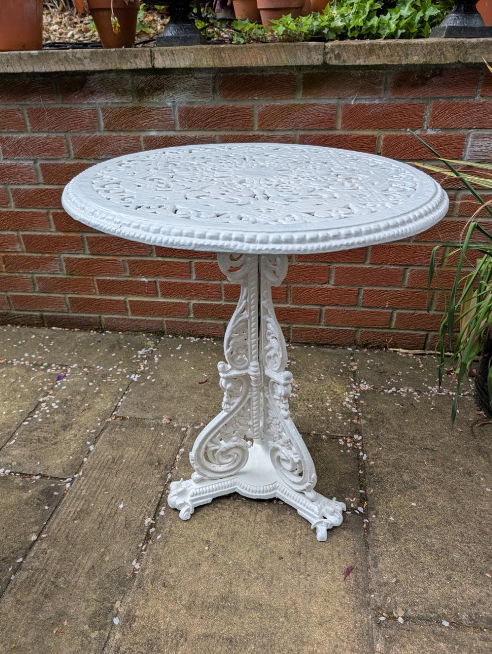 A white painted Victorian cast-iron garden bistro table featuring an intricately pierced circular top supported by an ornate tri-form pedestal base. View II
