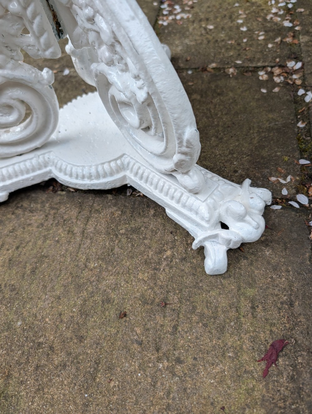 A white painted Victorian cast-iron garden bistro table featuring an intricately pierced circular top supported by an ornate tri-form pedestal base. View V
