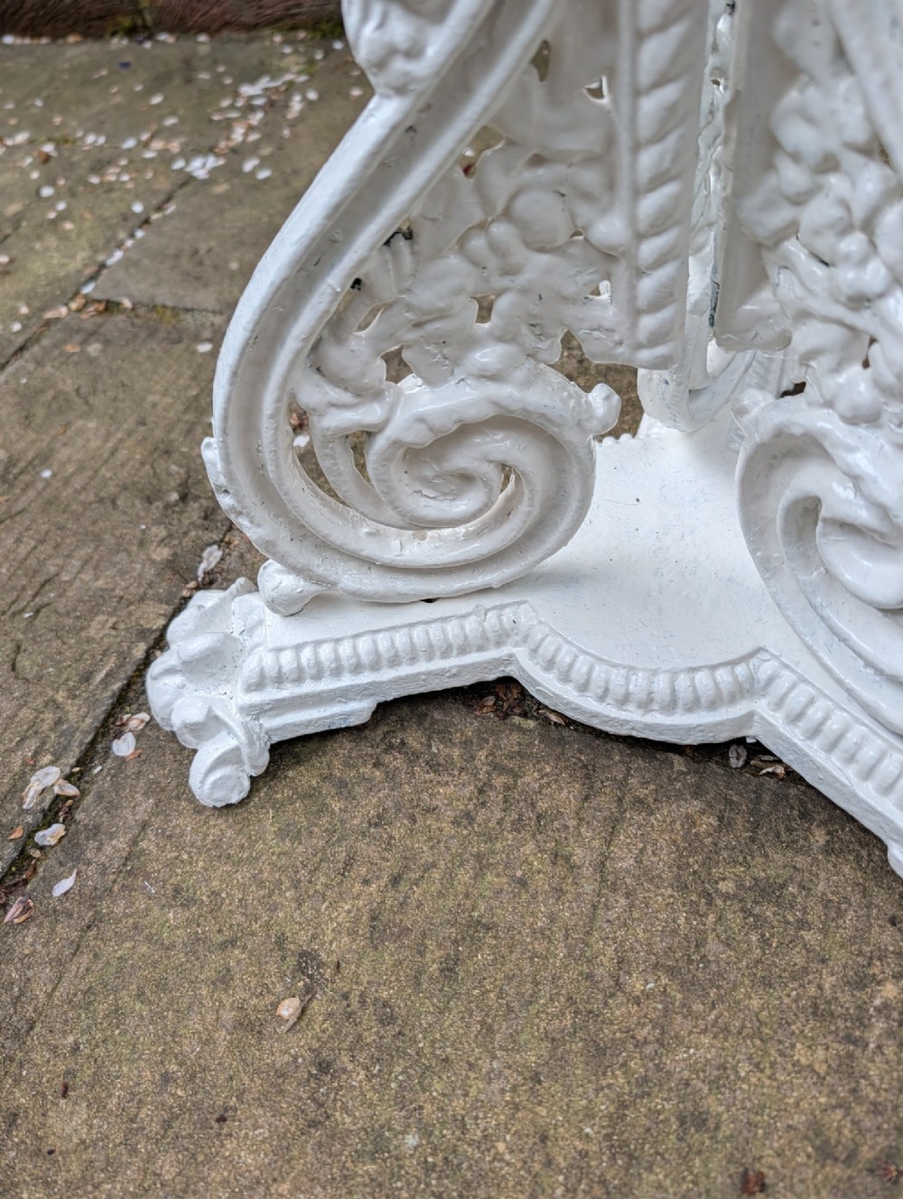 A white painted Victorian cast-iron garden bistro table featuring an intricately pierced circular top supported by an ornate tri-form pedestal base. View VI