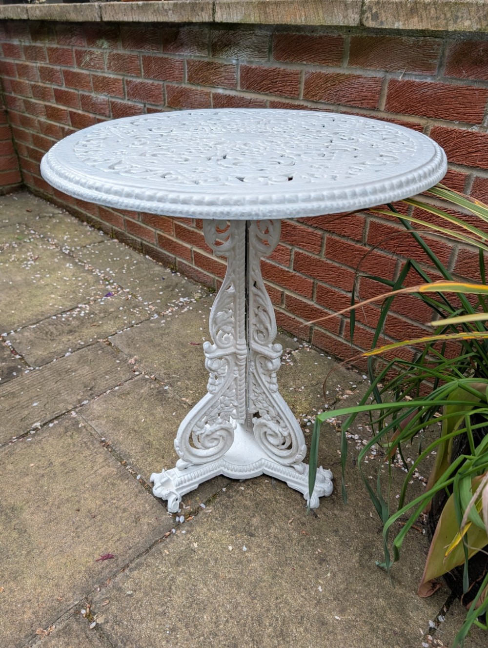 A white painted Victorian cast-iron garden bistro table featuring an intricately pierced circular top supported by an ornate tri-form pedestal base. View IX