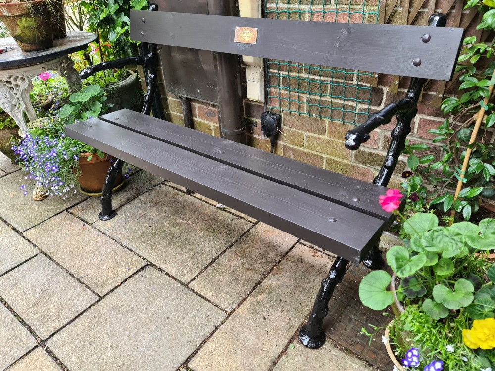 A 19th-century cast-iron and wooden garden bench featuring rustic branch-form end frames and a dark-stained timber seat and backrest. View II
