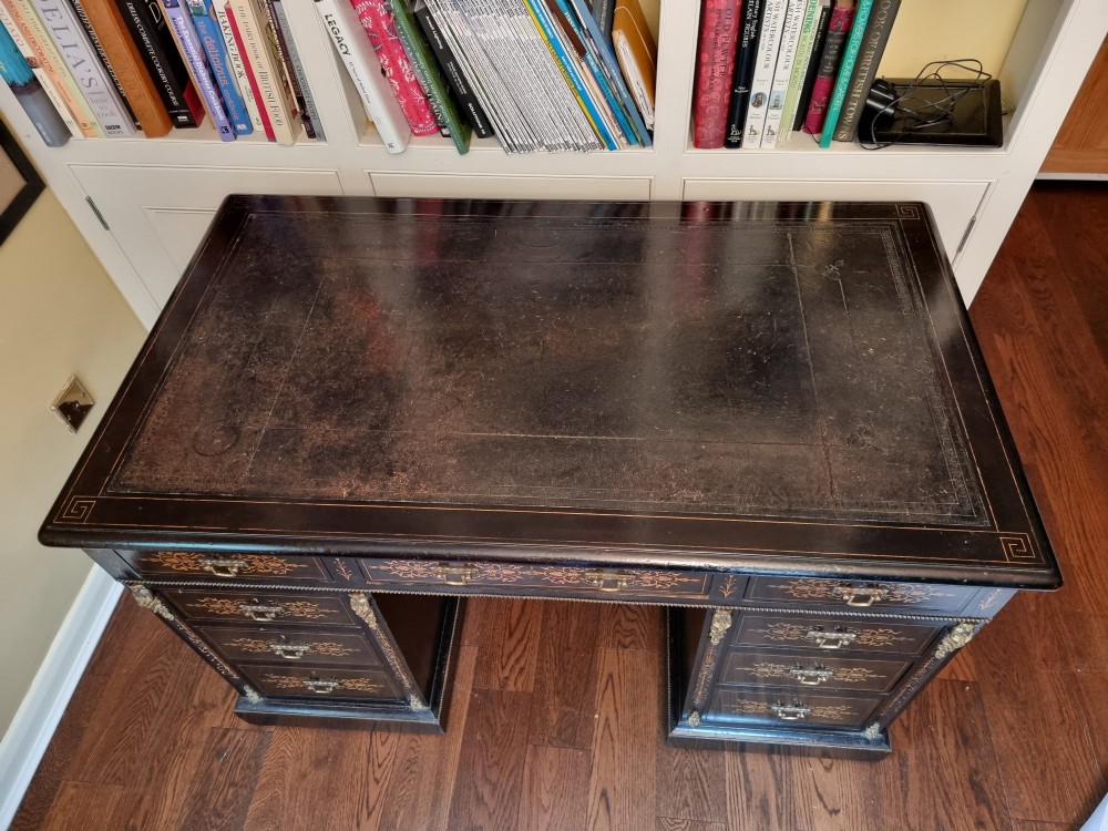 A Victorian ebonised wooden pedestal desk with floral marquetry inlay, leather insert top, brass handles, and gilt corner mounts. View II