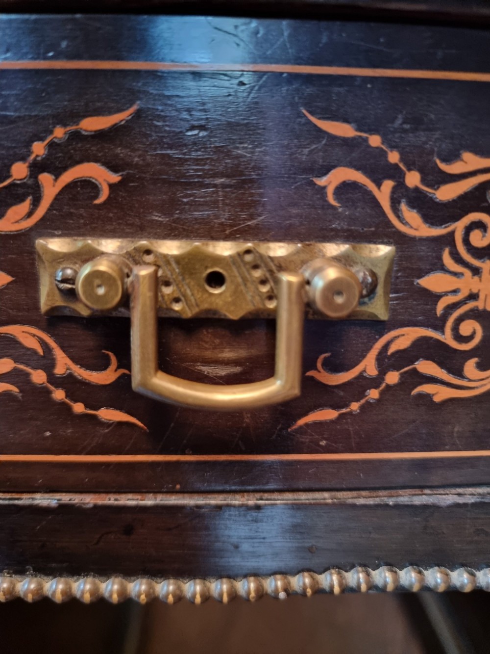 A Victorian ebonised wooden pedestal desk with floral marquetry inlay, leather insert top, brass handles, and gilt corner mounts. View X