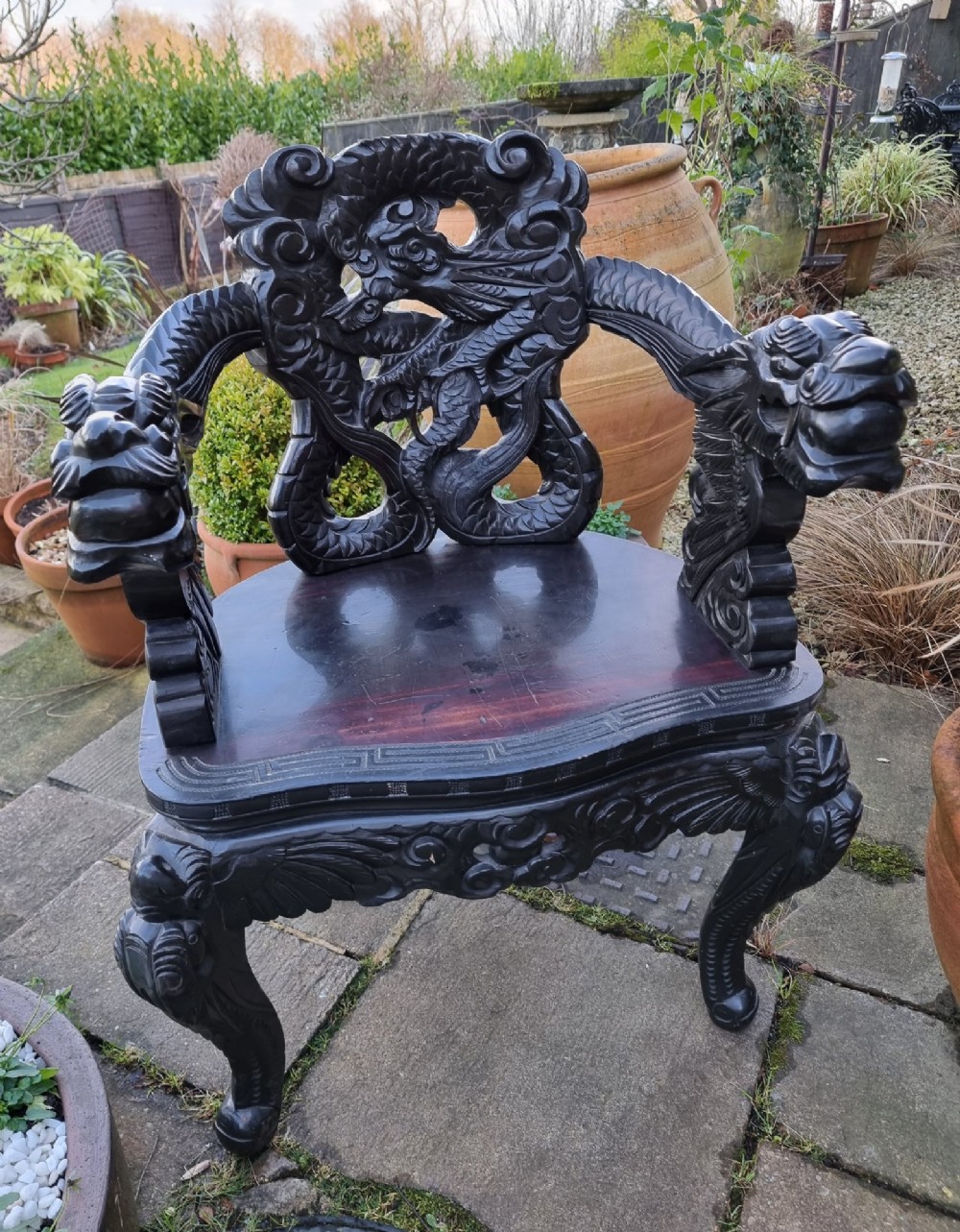 A deeply carved black hardwood armchair featuring dragon head armrests, a dragon backrest, and a red velvet seat cushion. View II
