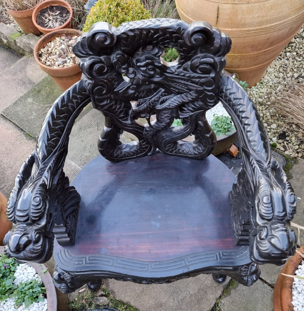 A deeply carved black hardwood armchair featuring dragon head armrests, a dragon backrest, and a red velvet seat cushion. View III
