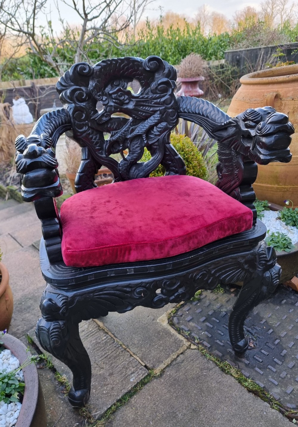 A deeply carved black hardwood armchair featuring dragon head armrests, a dragon backrest, and a red velvet seat cushion. View V