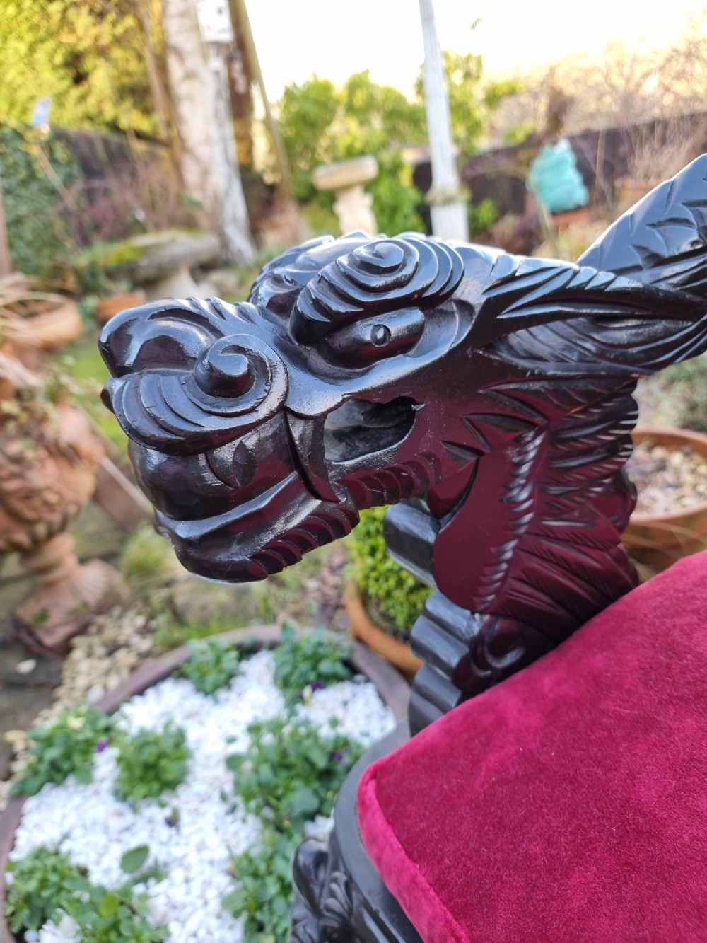 A deeply carved black hardwood armchair featuring dragon head armrests, a dragon backrest, and a red velvet seat cushion. View VII
