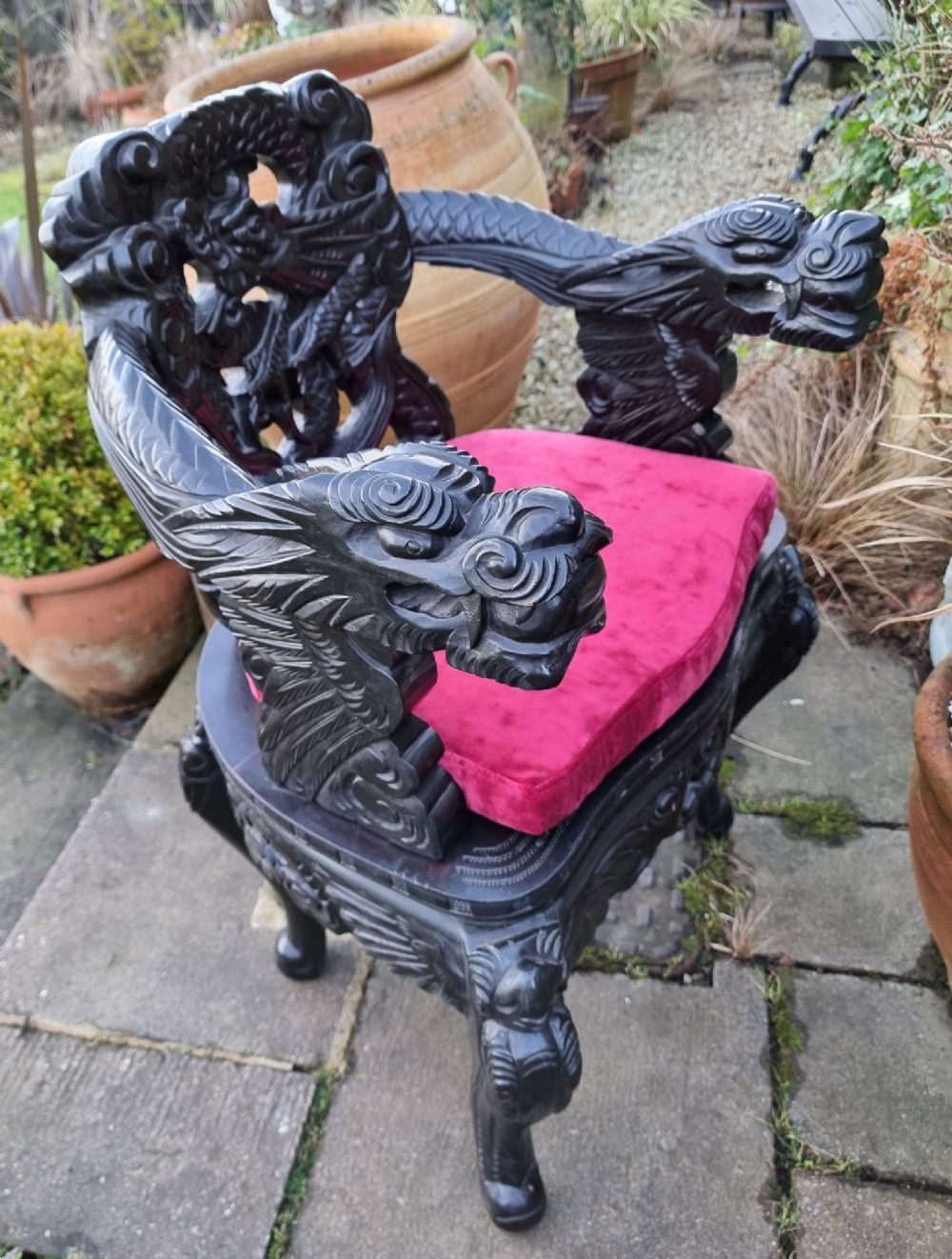 A deeply carved black hardwood armchair featuring dragon head armrests, a dragon backrest, and a red velvet seat cushion. View X