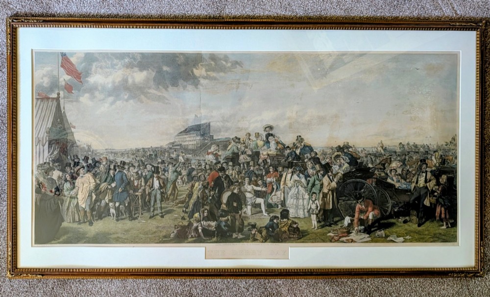 A panoramic 19th-century framed print depicting a densely populated scene at the Epsom Derby within a cream mount and gilt wooden frame.