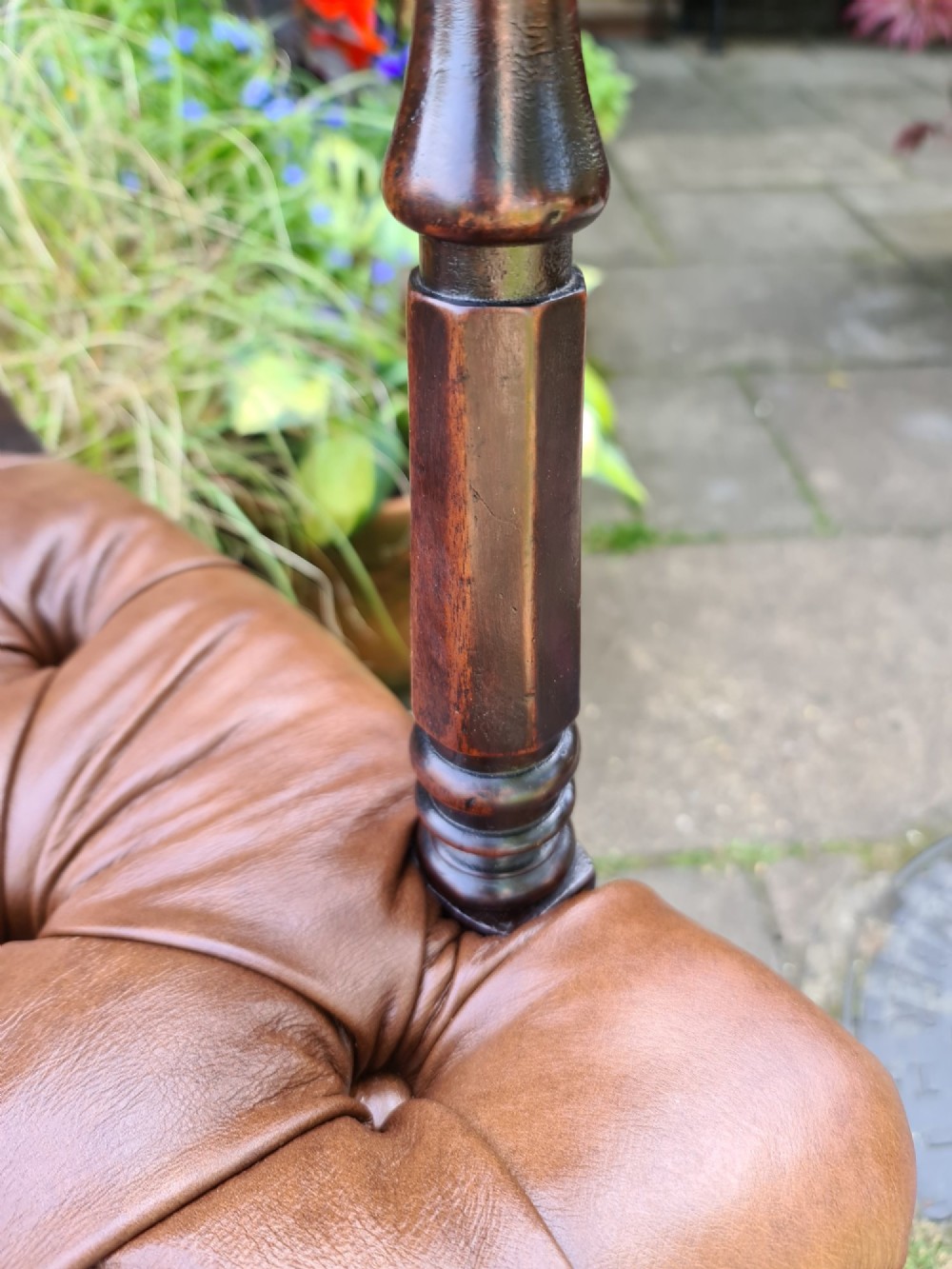 Early 19th-century mahogany desk chair featuring a curved back rail, turned front legs on brass castors, and a buttoned brown leather seat. View IV