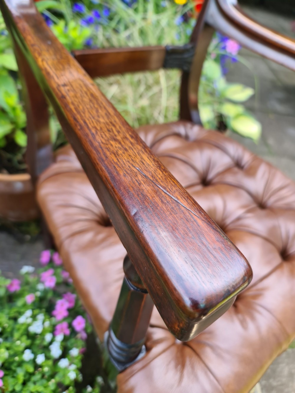 Early 19th-century mahogany desk chair featuring a curved back rail, turned front legs on brass castors, and a buttoned brown leather seat. View VI