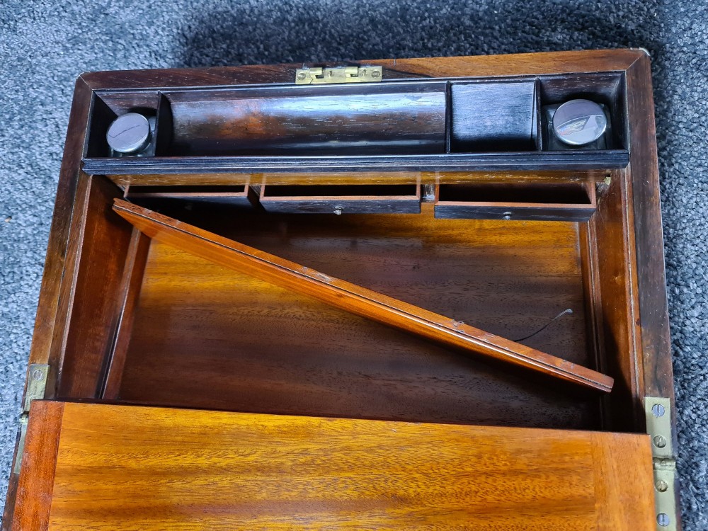 A rectangular rosewood box featuring brass edge binding, inlaid brass stringing, a brass escutcheon, and a tassel key inserted in the lock. View V