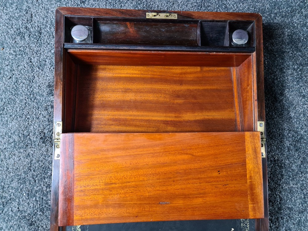 A rectangular rosewood box featuring brass edge binding, inlaid brass stringing, a brass escutcheon, and a tassel key inserted in the lock. View VI