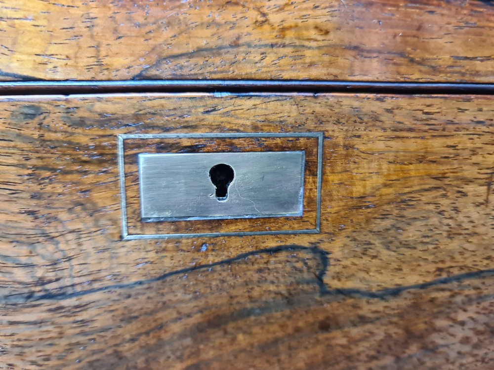 A rectangular rosewood box featuring brass edge binding, inlaid brass stringing, a brass escutcheon, and a tassel key inserted in the lock. View IX