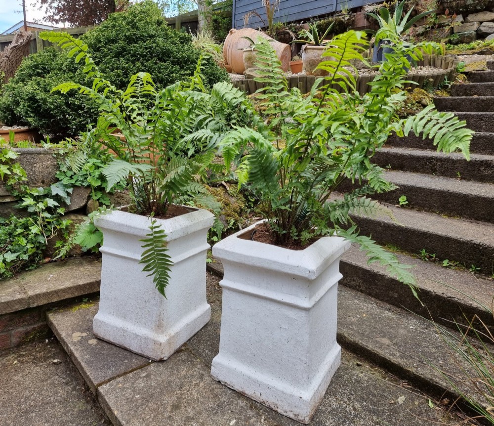 A pair of 19th-century square white-painted terracotta chimney pot pedestals with moulded rims resting on outdoor stone steps. View III