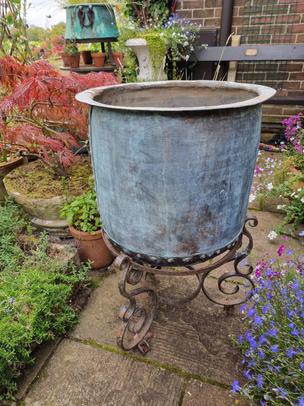 A large cylindrical French copper garden pot featuring a flared rolled rim, hand-riveted base seam, and a naturally weathered verdigris patina. View VI