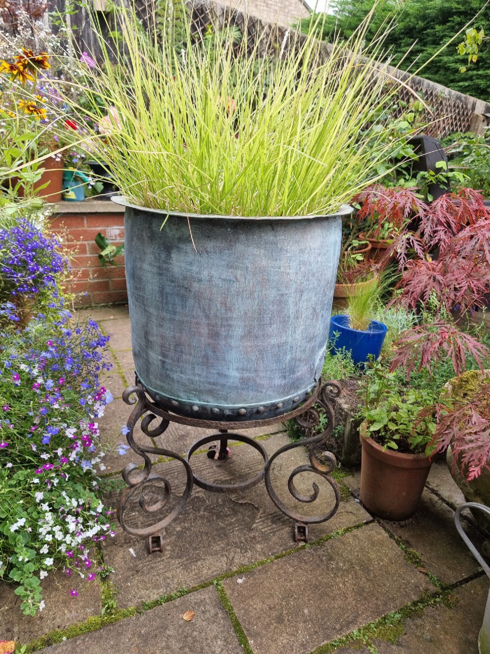 A large cylindrical French copper garden pot featuring a flared rolled rim, hand-riveted base seam, and a naturally weathered verdigris patina. View VII