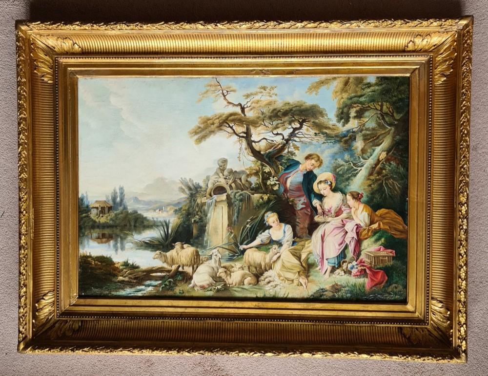 An oil painting depicting a Rococo pastoral scene with figures and sheep by a stream, set within a heavy gilded frame.