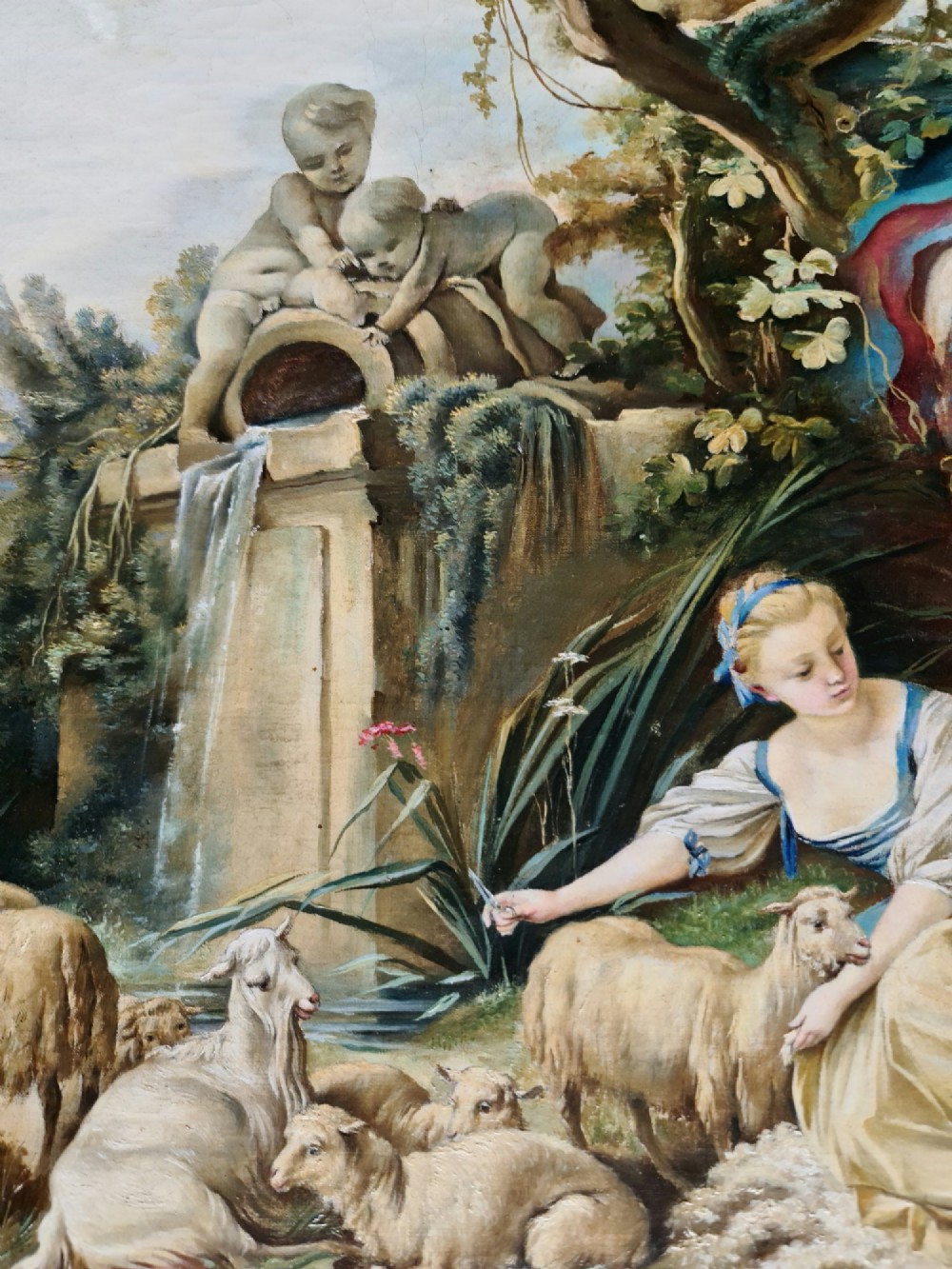 An oil painting depicting a Rococo pastoral scene with figures and sheep by a stream, set within a heavy gilded frame. View X