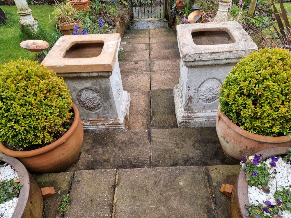 A pair of square weathered off-white painted terracotta pedestals featuring moulded floral medallion reliefs on each face. View VIII