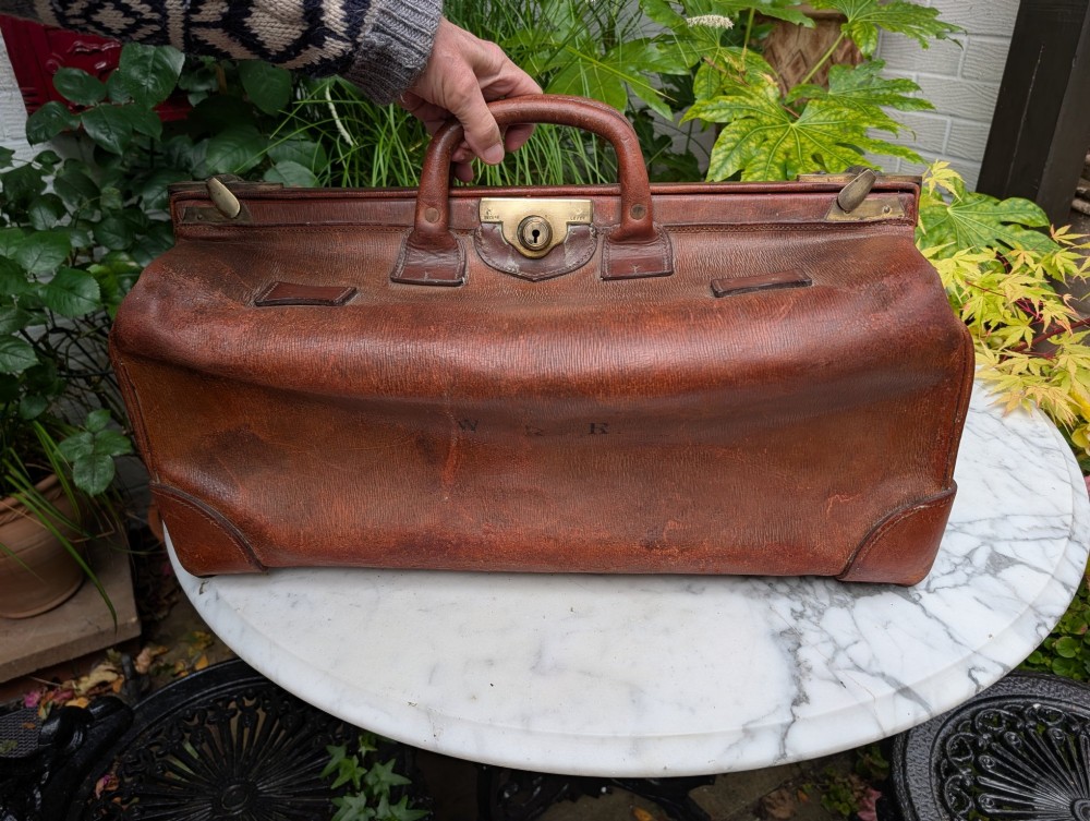 A Victorian brown leather Gladstone travel bag with a central brass lever lock and twin stitched handles.