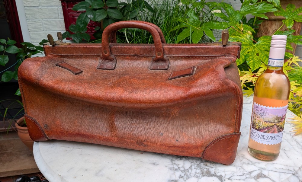 A Victorian brown leather Gladstone travel bag with a central brass lever lock and twin stitched handles. View III