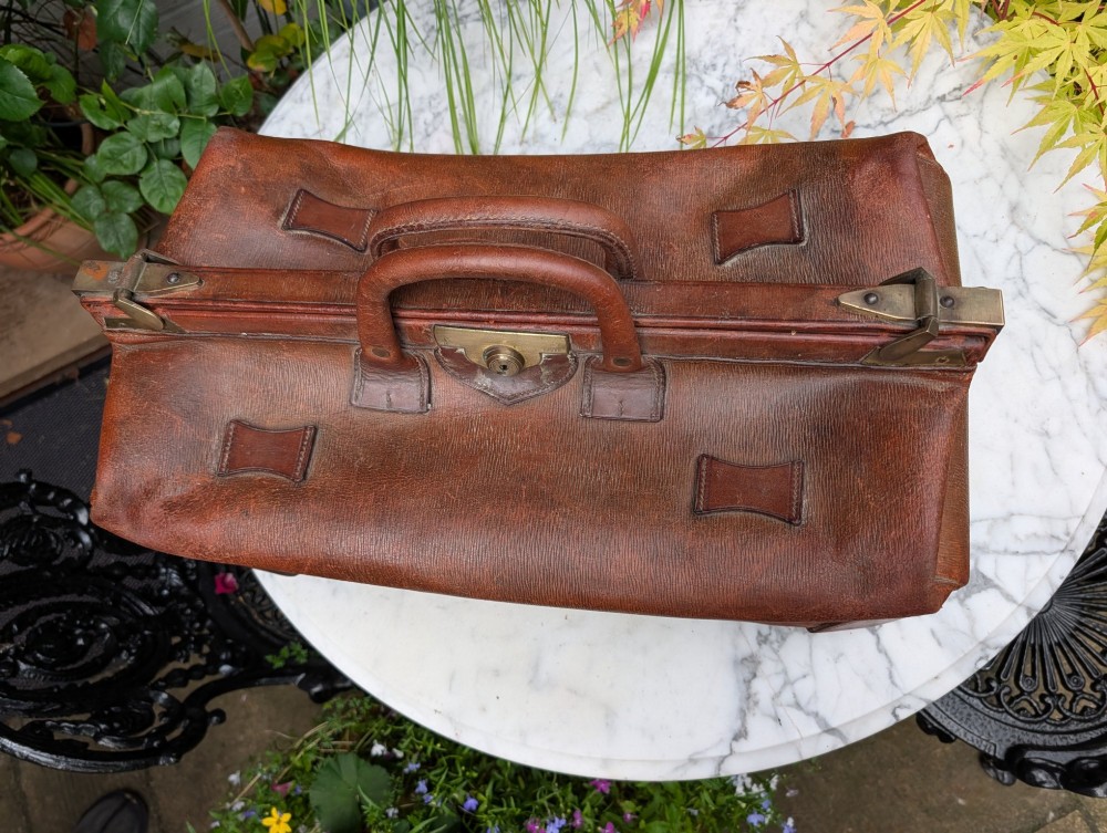 A Victorian brown leather Gladstone travel bag with a central brass lever lock and twin stitched handles. View IV