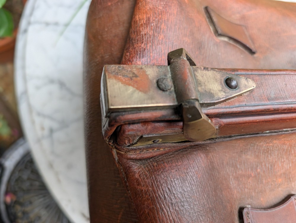 A Victorian brown leather Gladstone travel bag with a central brass lever lock and twin stitched handles. View VII