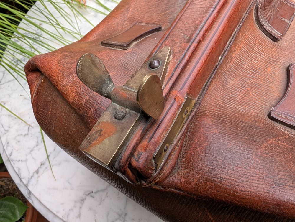 A Victorian brown leather Gladstone travel bag with a central brass lever lock and twin stitched handles. View VIII