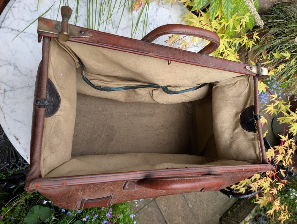 A Victorian brown leather Gladstone travel bag with a central brass lever lock and twin stitched handles. View IX