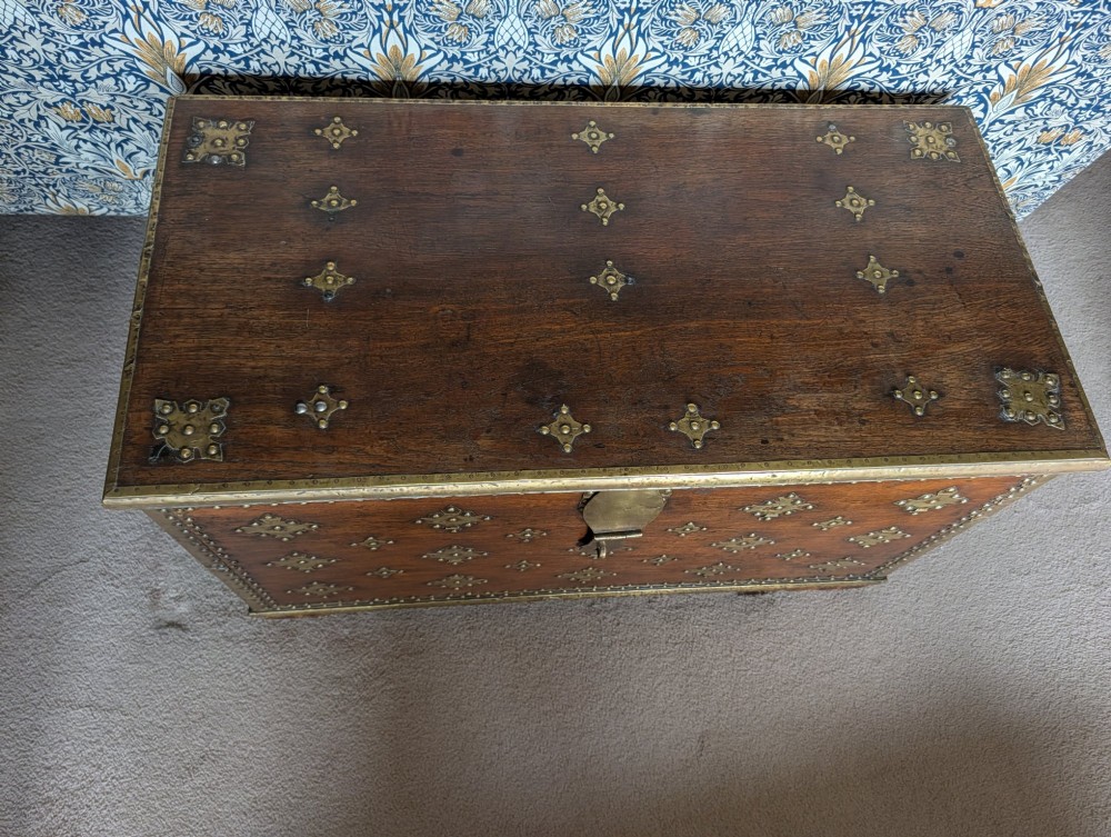 An antique padouk wood Zanzibar chest decorated with geometric brass studs, pierced brass plaques, and heavy iron side handles. View IV