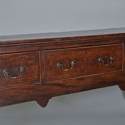 fig 1. An 18th-century warm brown elm dresser base featuring three drawers with brass drop handles and square legs.